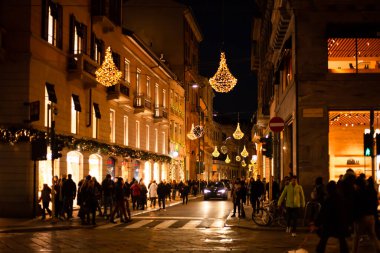 Milano, İtalya 'da, 2.12.2023' te insanların alışveriş torbalarıyla gezdiği yılbaşı sokak ışıklarının bulanık arkaplanı.