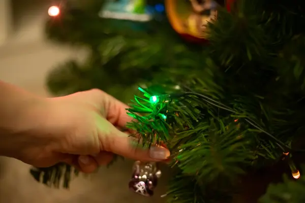 Decorating Christmas tree, close up, copy space. Merry Christmas and Happy New Year. Women hands decorate the Christmas tree with balls and toys.
