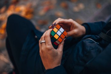 İtalya, Milano 20.11.2023: Yaratıcı fikirler kavramı. Elinde bir Rubik küp tutan bir kız. Bir bulmacanın çözümünü arayan bir kadın. Rebus, yap-boz. - Evet. Yüksek kalite fotoğraf