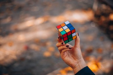 İtalya, Milano 20.11.2023: Yaratıcı fikirler kavramı. Elinde bir Rubik küp tutan bir kız. Bir bulmacanın çözümünü arayan bir kadın. Rebus, yap-boz. - Evet. Yüksek kalite fotoğraf