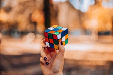 İtalya, Milano 20.11.2023: Yaratıcı fikirler kavramı. Elinde bir Rubik küp tutan bir kız. Bir bulmacanın çözümünü arayan bir kadın. Rebus, yap-boz. - Evet. Yüksek kalite fotoğraf