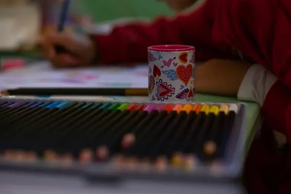 The girl draws with colored pencils. POV child painting a picture with school supplies, preschool child painting, child doing homework. High quality photo