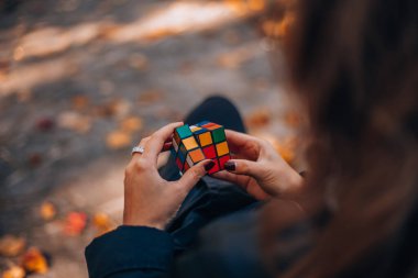 İtalya, Milano 20.11.2023: Yaratıcı fikirler kavramı. Elinde bir Rubik küp tutan bir kız. Bir bulmacanın çözümünü arayan bir kadın. Rebus, yap-boz. - Evet. Yüksek kalite fotoğraf