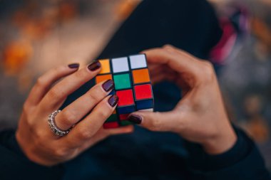 İtalya, Milano 20.11.2023: Yaratıcı fikirler kavramı. Elinde bir Rubik küp tutan bir kız. Bir bulmacanın çözümünü arayan bir kadın. Rebus, yap-boz. - Evet. Yüksek kalite fotoğraf