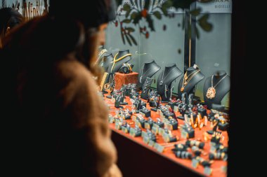 Milan, İtalya 11.12.2023 Showcase ve Milan 'ın merkezinde Piazza Duomo' da mücevherleri var. Bir kadın dükkanın camına bakar ve arkadaşı için bir hediye seçer. Yüksek kalite fotoğraf