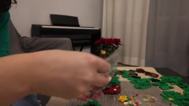 Bir kız evde yeni yıl ağacı şeklinde bir lego seti topluyor. Yüksek hızlı video. İtalya, Milan 01.01.2024. Yüksek kalite 4k görüntü