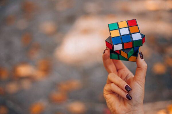 ITALY, MILAN JANUARY 29, 2024: Rubiks Cube was invented in 1974 by Hungarian sculptor and professor of architecture Erno Rubik. Hands of a young lady trying to solve the puzzle. High quality photo