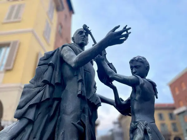 İtalya, Cremona 03.2024 Cremona Stradivarius Anıtı. Antonio Stradivari 'nin bronz heykeli. Cremona 'daki Piazza Stradivari Anıtı' nda bir keman ve bir çocukla Luthier. Yüksek