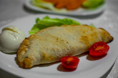 Calzone Doldurulmuş Pizza. Ev yapımı İtalyan eti ve soslu peynirli Calzones. Beyaz tabakta Mozzarella peyniri ve domates. Yüksek kalite fotoğraf