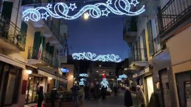 İtalya, Stresa 01.01.2024. Noel için süslenmiş güzel bir cadde. Cadde turistlerle dolu. Yeni yıl ve Noel tatili kavramında parlayan kardan adam. - Evet. Yüksek kaliteli FullHD görüntüler