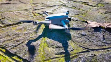 Mini bir dron taş bir platformdan güneşli bir platforma doğru havalanıyor. Yerden havalanan küçük bir İHA 'nın yakınında. İnsansız hava aracını yavaş çekimde kullanmak..