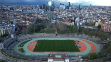 Şehir ve stadyum sahası ve koşu pisti Arena Civica ile. Sempione Park 'taki bahar ağaçlarının insansız hava aracı görüntüsü. Modern gökdelenlerin manzarası. Ekoloji. Yeşil Gezegen Milan mı? İtalya. 