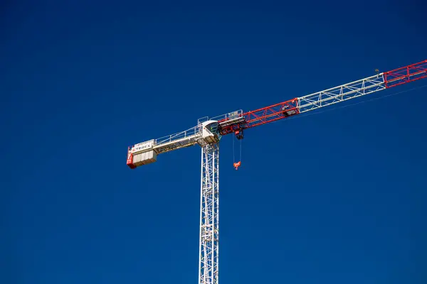 Construction cranes work on creation site against blue sky background. Bottom view of industrial crane. Concept of construction of apartment buildings and renovation of housing.