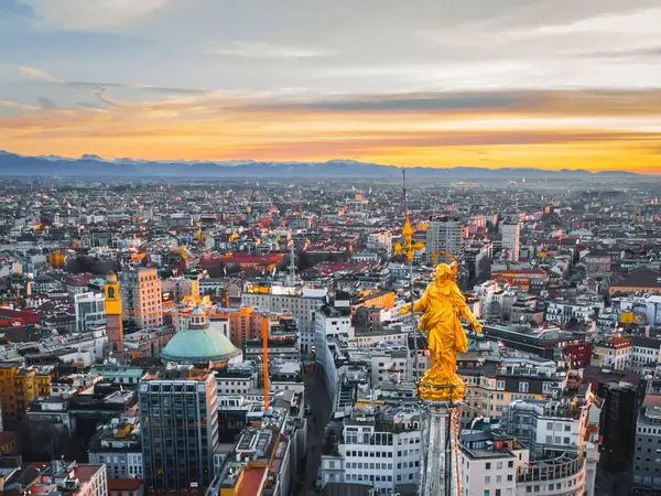Duomo Katedrali 'nin Meryem Ana heykelinin hava manzarası gün batımında şehir manzarasının arka planına karşı.. 