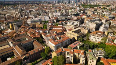 Milano Üniversitesi 'nin çatısı ve şehir binaları manzaranın en aşağısında. Milano şehir manzarası mavi gökyüzünün arka planına karşı, yukarıdan güneşli hava manzarası. 