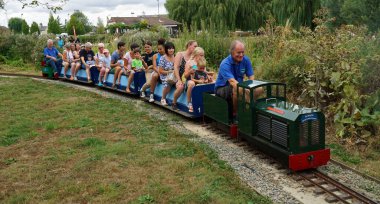 St. NEOTS, CAMBRIDGESHIRE, İngiltere - 24 AĞUSTOS 2022: İnsanlar parkta minyatür tren yolculuğunun keyfini çıkarıyorlar.