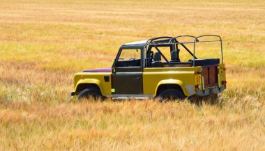 BLAKENEY, NORFOLK, ENGLAND -  JULY 13, 2022: Land Rover Defender parked in field of wheat