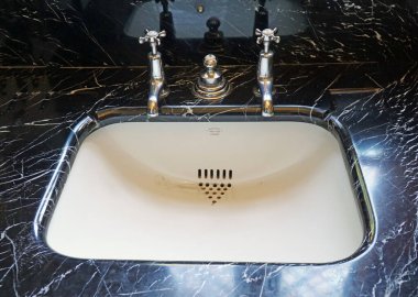 SAFFRON WALDEN, ESSEX, İNGİLTAN - Eylül 05, 2023: Vintage Lavabo ve Musluklar Siyah Mermer Üst Beyaz Lavabo ve Krom Musluklar.