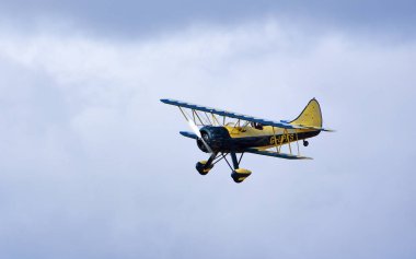 Küçük Gransden, CAMBRIDGESHIRE, İngiltere - 27 AĞUSTOS 2023: Vintage Waco UPF-7 çift kanatlı bulutlara karşı uçuyor.