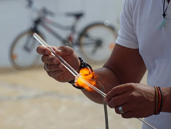 Hands making glass sculpture with flame and glass rods