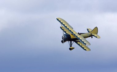 Küçük Gransden, CAMBRIDGESHIRE, İngiltere - 27 AĞUSTOS 2023: Vintage Waco UPF-7 çift kanatlı bulutlara karşı uçuyor.