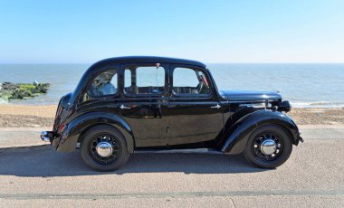 FELIXSTOWE, SUFFOLK, ENGLAND - MAYIS 06, 2018: Arka planda deniz kenarına park edilmiş klasik Black Austin 8 Salonu.