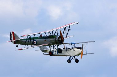 ICKWELL, BEDFORDSHIRE, ENGLAND - SEPTEMBER 06, 2020:  Vintage 1933 Avro 621 Tutor and De Havilland Moth in flight. clipart