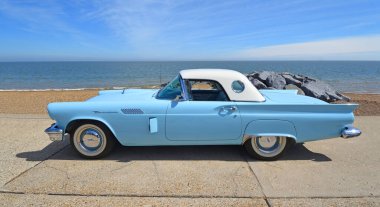 FELIXSTOWE, SUFFOLK, ENGLAND - MAYIS 05, 2024: Klasik 1957 Ford Thunderbird Amerikan otomobili plaj ve denizin arka planında deniz kenarına park edilmiş..