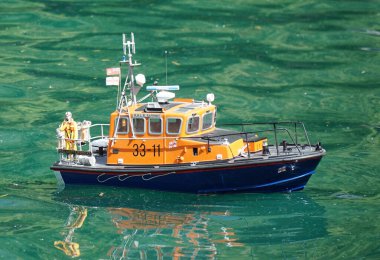 KETTERING, NORTHAMPTONSHIRE, ENGLAND - MAY 25, 2024: Model Boat RNLI rescue boat on boat pond. clipart