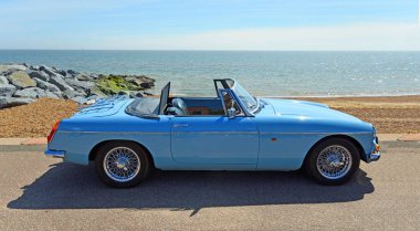 FELIXSTOWE, SUFFOLK, ENGLAND - MAYIS 05, 2024: Arka plandaki Iris Blue 'da park etmiş MGB Roadster yarışı tamamladı.