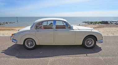 FELIXSTOWE, SUFFOLK, ENGLAND - MAYIS 05, 2024: Arka planda deniz ve deniz kenarına park edilmiş klasik Jaguar MK2 motorlu araç