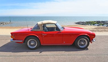 FELIXSTOWE, SUFFOLK, ENGLAND - MAYIS 05, 2024: Arka planda deniz ve deniz kenarında klasik Triumph TR6 Motorlu Araç