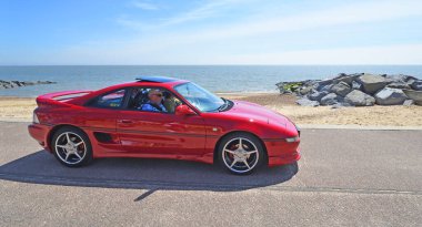 FELIXSTOWE, SUFFOLK, ENGLAND - MAY 05, 2024:  Classic  Red  Toyota MR2 being driven along seafront clipart