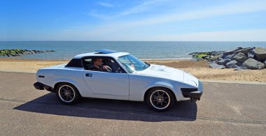 FELIXSTOWE, SUFFOLK, ENGLAND - MAYIS 05, 2024: Klasik beyaz Triumph TR7 deniz kenarı boyunca sürülüyor
