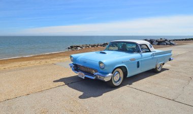 FELIXSTOWE, SUFFOLK, ENGLAND - MAYIS 05, 2024: Klasik 1957 Ford Thunderbird Amerikan otomobili plaj ve deniz manzaralı deniz gezintisi.