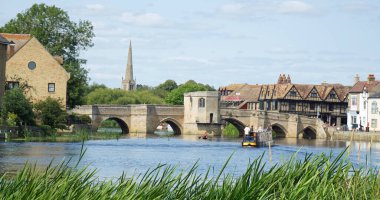 ST IVES, CAMBRIDGESHIRE, İngiltere - 17 AĞUSTOS 2024: ST IVES, CAMBRIDGESHIRE, ENGLAND - 17 AĞUSTOS 2024: St Ives Kambridgeshire 'deki Ouse nehri üzerinde dar bir tekne ile köprü