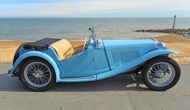 FELIXSTOWE, SUFFOLK, ENGLAND - MAYIS 05, 2024: Arka planda deniz kenarında park etmiş klasik Açık Mavi MG aracı