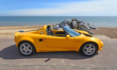 FELIXSTOWE, SUFFOLK, ENGLAND - MAYIS 05, 2024: Arka planda deniz ve deniz kıyısında klasik Sarı Lotus Elise S1 spor arabası. 