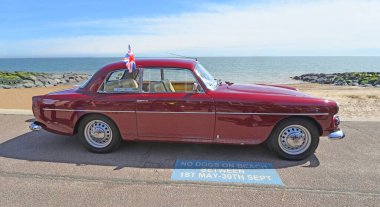 FELIXSTOWE, SUFFOLK, ENGLAND - MAYIS 05, 2024: Arka planda deniz kenarında park etmiş klasik Red Bristol motorlu araç