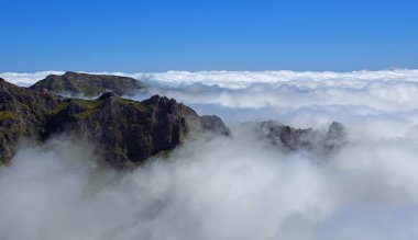 Pico do Areeiro Madeira tepeleri üzerinde mavi gökyüzü olan bulutların arasında.