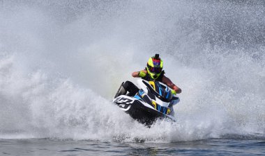 Jet Ski yarışçısı hızla viraj alıyor ve bir sürü sprey püskürtüyor.