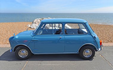 FELIXSTOWE, SUFFOLK, ENGLAND - MAYIS 05, 2024: Arka planda deniz ve deniz kenarına park edilmiş klasik mavi Mini motorlu araç