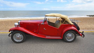 FELIXSTOWE, SUFFOLK, ENGLAND - MAYIS 04, 2025: Arka planda deniz kenarına park etmiş yumuşak bir üstü olan klasik Red MG TD