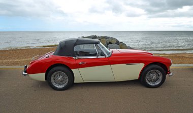 FELIXSTOWE, SUFFOLK, ENGLAND - MAYIS 04, 2025: Arka planda deniz kenarında park edilmiş klasik Autin Healey 3000.