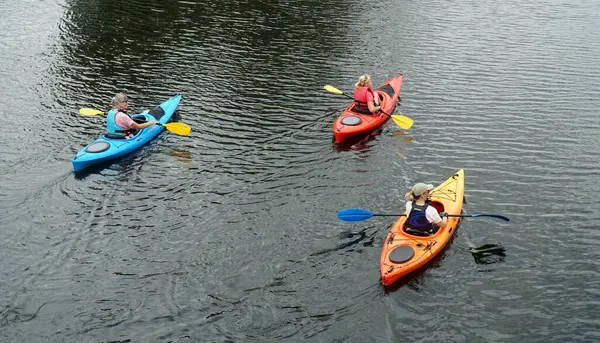 St Ives, Cambridgeshire, İngiltere - 09 Temmuz 2025: Ouse nehrinde renkli kanolar içinde üç kişi