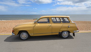 FELIXSTOWE, SUFFOLK, ENGLAND - MAYIS 05, 2024: Klasik 1972 Saab 95 V4 Malikânesi arka planda deniz kenarına park edilmiş. 