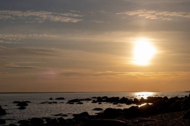 Sahilde güzel bir gün batımı deniz dalgaları ve bulutlar kıyıda alacakaranlıkta.