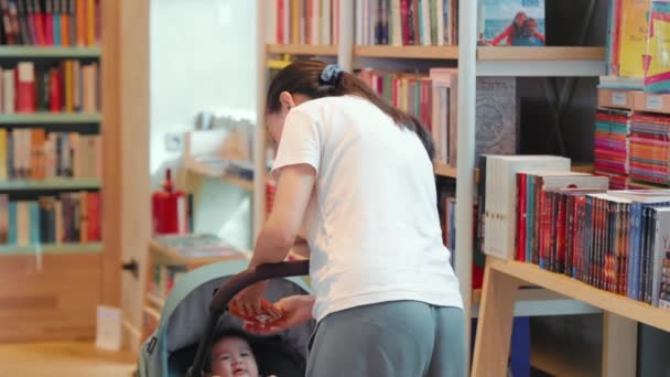 Jeune Mère Montre Livre Coloré Bébé Dans Une Librairie Images — Video