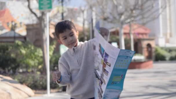 亚洲小男孩正在看一个旅游胜地的纸质地图 高质量的4K镜头 — 图库视频影像