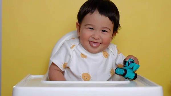 Bonito Bebê Asiático Senta Cadeira Alta Sorrindo Fundo Amarelo Imagens — Fotografia de Stock